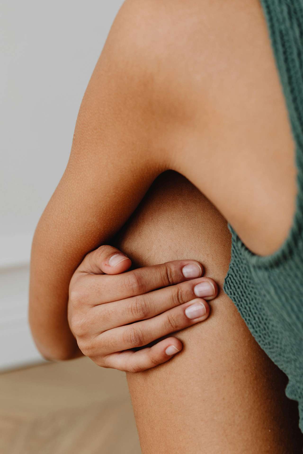 La tua pelle non dorme mai. E tu cosa le fai indossare? Donna con canottiera che si tocca la pelle.
